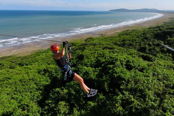 Person ziplining above forest with expansive ocean view near Cartagena