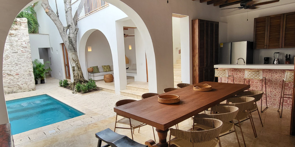 Casa Perla. Open Kitchen with long wooden table facing onto the outside pool