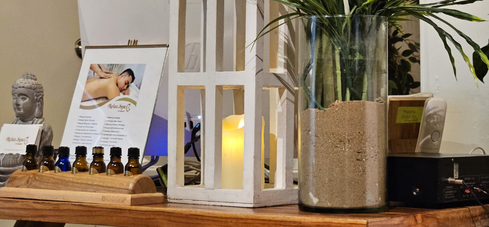 Cozy spa setup featuring essential oils, a massage service menu, a candle-lit lantern, and a peaceful Buddha statue at Relax Spa Cartagena.